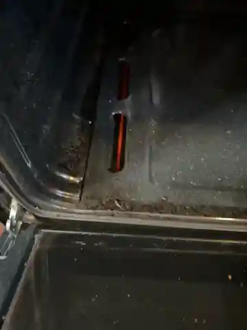 Orange oven igniter glow visible through slots in the Whirlpool oven floor